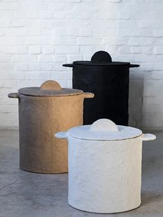 three pots sitting next to each other in front of a white brick wall and floor