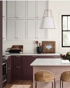 a kitchen with two stools in front of the island