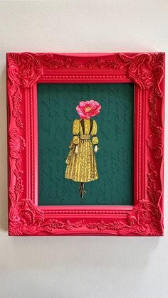 a red frame with a paper cut out of a woman in a yellow dress holding a pink flower