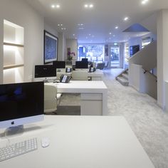 an office with white desks and computers on the counter top in front of stairs