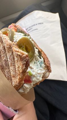 a person holding a sandwich in their hand with some sort of toppings on it