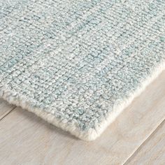 a close up view of a rug on a wooden floor with light blue and white colors