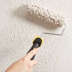 a person using a roller to paint a wall