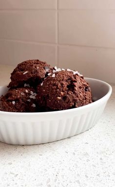 a white bowl filled with chocolate cookies on top of a counter