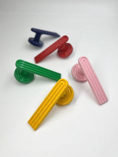 four different colored plastic handles on a white surface