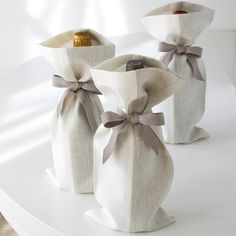 two white vases with bows on them sitting on a shelf next to each other