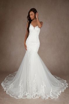 a woman in a white wedding dress posing for the camera with her hand on her head