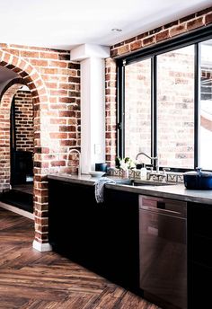 a kitchen with brick walls and black cabinets