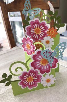 a card with flowers and butterflies on it sitting on top of a table next to a window