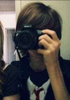 a woman taking a selfie in front of a mirror with a camera on her shoulder