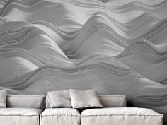 a white couch sitting in front of a wall with waves on it's side