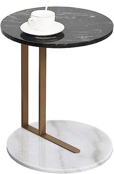 a black marble table with gold legs and a white bowl sitting on top of it