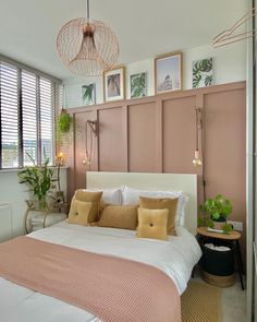 a bedroom with pink walls and white bedding, potted plants on the wall