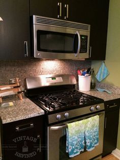 a stove top oven sitting inside of a kitchen next to a microwave and dish towel rack