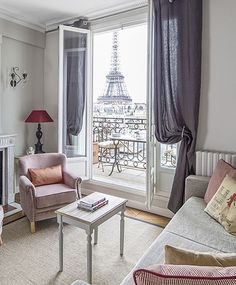 a living room filled with furniture and a large window overlooking the eiffel tower