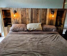 a bed made out of wood with two lights on each side and one light at the headboard