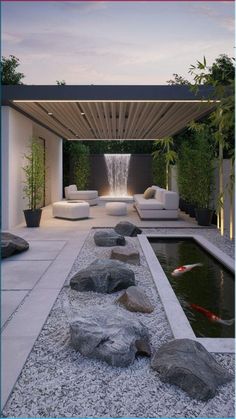 an outdoor living area with water feature and rocks in the foreground, surrounded by white couches