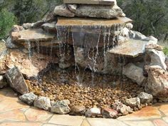 an outdoor fountain with rocks and water flowing from it