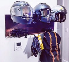 two helmets are hanging on a wall with gloves and backpacks attached to it's hooks