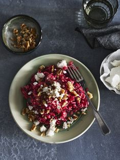 a white plate topped with beet salad next to two bowls of yogurt