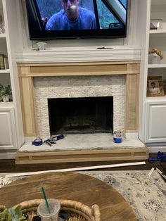 a man sitting in front of a tv on top of a fire place