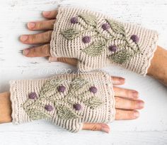 two hands wearing knitted gloves with flowers on them