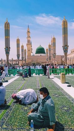 two men sitting on the ground in front of an ornate building with green domes and gold trimmings