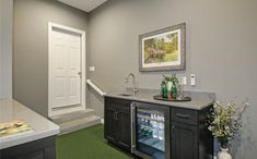 a kitchen area with refrigerator, sink and green carpeted flooring in front of the door