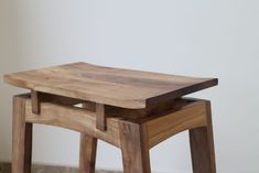 two wooden stools sitting next to each other on top of a tile floor in front of a white wall