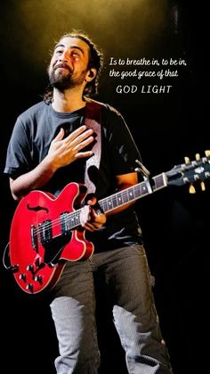 a man holding a red guitar in his right hand with a quote on the left