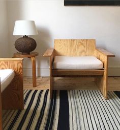 a room with two chairs and a lamp on the floor in front of a white wall