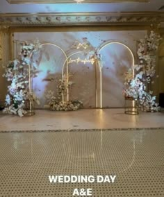 an indoor wedding ceremony setup with white flowers and gold arches on the wall behind it