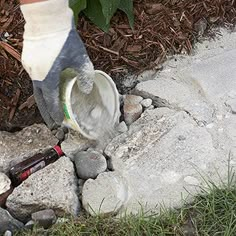 a person in socks is pouring cement into a hole with a beer bottle next to it