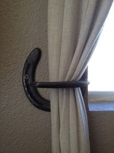 the curtain rod is hanging on the wall by the window with it's black handle