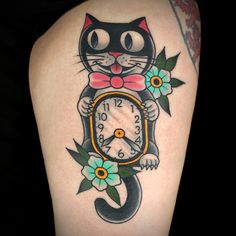 a black cat with a bow tie and flowers around its neck is holding a clock