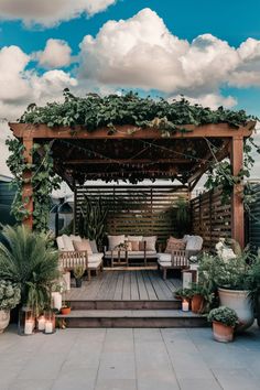 Covered outdoor seating area with wooden pergola, lush green plants, white cushions, and decorative string lights. Patio Covering Ideas, Patio Shade Ideas, Patio Cover Ideas, Patio Covering, River Garden, Shade Ideas, Shade Screen, Hanging String Lights, Custom Canopy