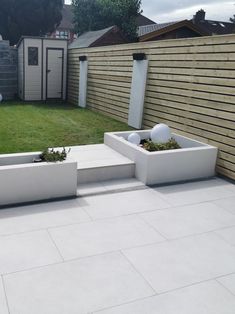 an outdoor garden with white planters and grass