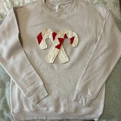 a white sweater with red and white ribbon on the front is laying on a bed