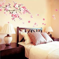 a bed room with a neatly made bed and a flower wall decal on the wall