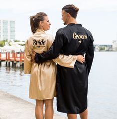 two people in robes standing next to the water