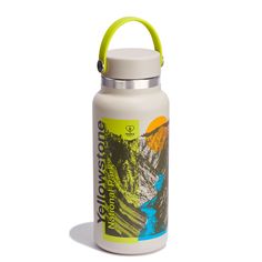 a white water bottle with a green handle on the side and mountains in the background