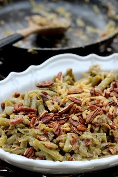 a white bowl filled with green beans and pecans