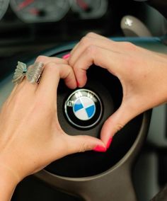 a woman's hands on the steering wheel of a bmw car, while she is driving