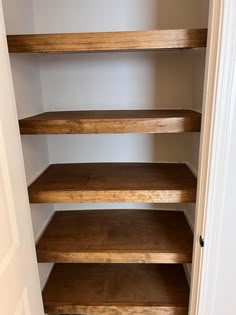 an empty closet with wooden shelves in it