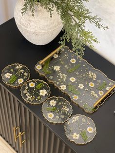 three trays with flowers on them are sitting on a table next to a plant