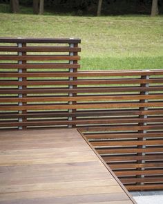 a wooden bench sitting on top of a sidewalk next to a lush green park filled with trees