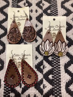 three pairs of leather earrings with flower designs on the front and back of each pair