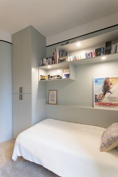 a white bed sitting in a bedroom next to a book shelf