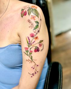 a woman with a flower tattoo on her arm and shoulder, sitting in a chair