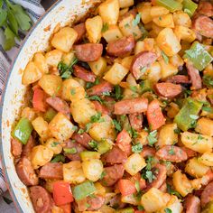 a pan filled with sausage and vegetables on top of a table